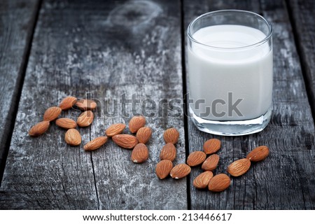 Almond milk, nuts and glass of tasty milk on old wooden table