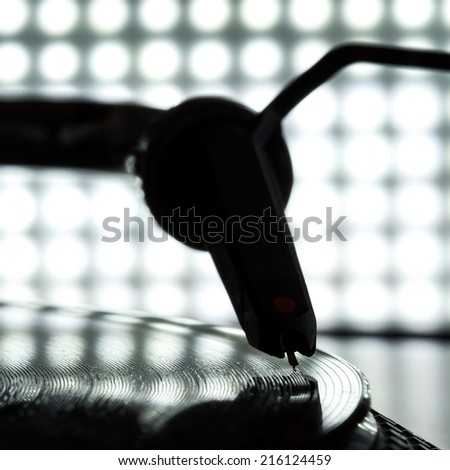 Dj needle stylus on spinning record, blur light background
