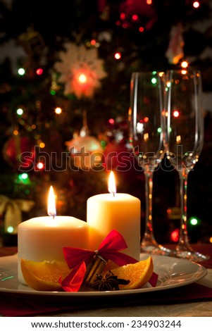 Christmas decoration, candles, cinnamon sticks and pieces of orange against Christmas lights