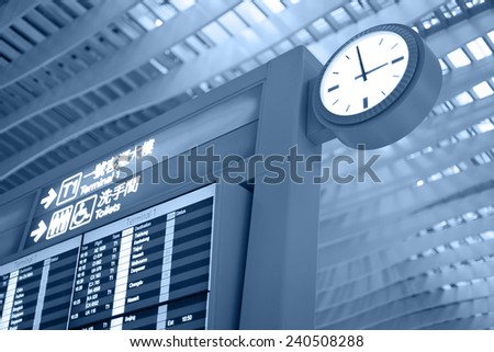 Big airport clock close to arrival board in airport terminal. Travel concept.