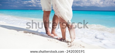 Close up male and female feet on white sand, kissing