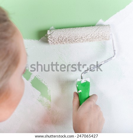Woman paints the wall, closeup