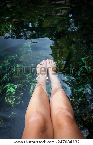 Fish spa therapy with female legs in mexican cenotes