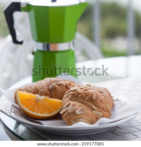 Delicious breakfast with coffee on hotel\'s balcony, fresh croissants and slice of orange fruit with   coffee percolator background