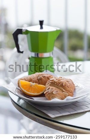 Delicious breakfast with coffee on hotel\'s balcony, fresh croissants and slice of orange fruit with   coffee percolator background
