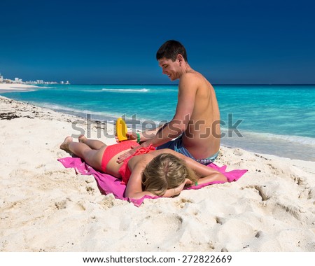 Man applying sun lotion on a woman back, summer tropical beach vacation