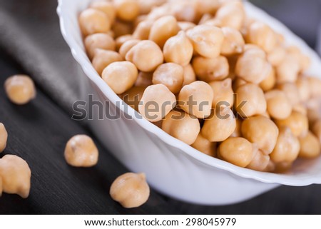 Raw wet gold chickpeas in bowl on wooden board, healthy vegan food with a lot protein, macro shot, selective focus