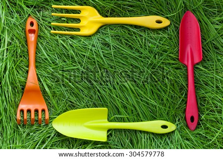 Set of gardening tools on green grass background. Plastic mini shovels, forks and spade. Selective focus