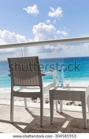 Balcony with plastic bottle of water on wicker table overlooking an ocean