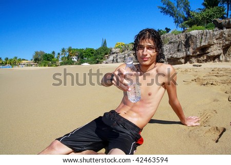 Man with bottle of water in hand on beach