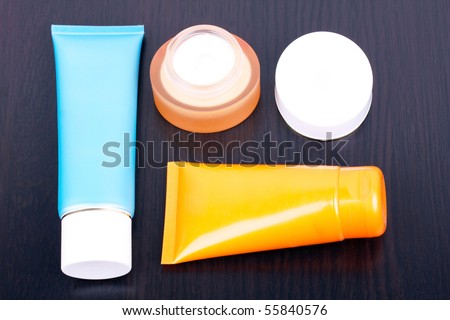 Tubes and box with cream on black table, closed-up