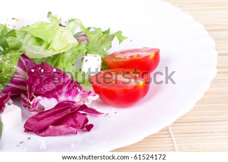 Salad with green and red leafs,tomato and sheep cheese on plate,closed-up