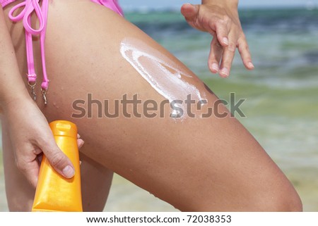 Woman applying on leg sun protection cream on beach