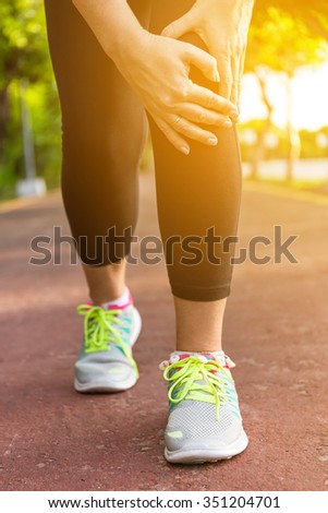 Female athlete runner touching foot in pain,closeup, fitness woman running in summer park. Healthy lifestyle and sport concept