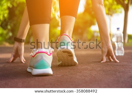 Fitness woman training and jogging in summer park. Ready to start. Healthy lifestyle and sport concept