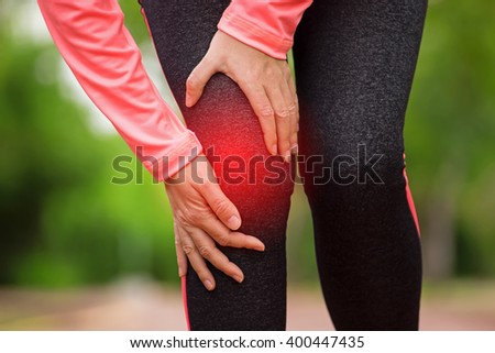 Female athlete runner touching Knee in pain, fitness woman running in summer park. Healthy lifestyle and sport concept