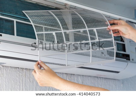 Dirty filter of air conditioner in female hands. Cleaning and washing maintenance