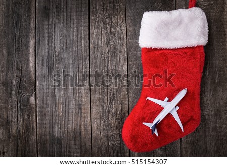 White blank toy of passenger plane on christmas decoration stocking over rustic wooden background. New Year celebration in travel
