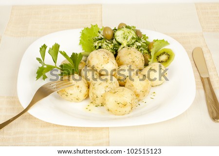 Early boiled potatoes with salad closeup