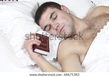 a young boy fell asleep with the Bible in the hands of a white bed