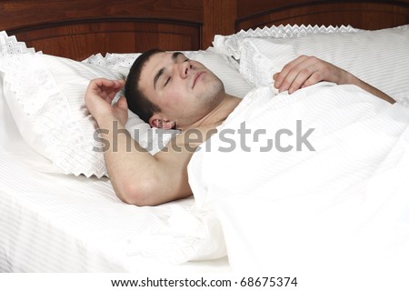 a young boy sleeps in a bed on the white sheet