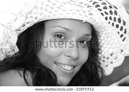 Fine art close-up black and white portrait of beautiful young lady turning toward viewer with white hat
