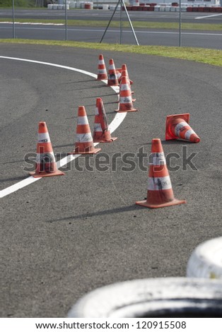 orange striped cones and a safety band of tyres on the motorbike track, motoGP, no trademarks visible
