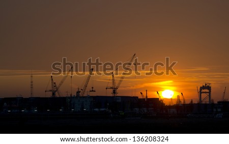 Industrial construction cranes silhouettes at sunset in the port of Rotterdam, the Netherlands