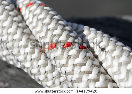 The black and white texture of a close-up of twisted ship cord with red accents only