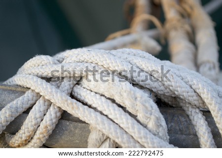 Sailor hawser rope moored to the old worn wooden pier of marina on water background