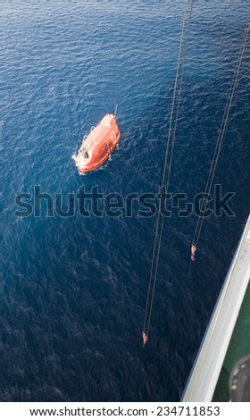Lowered orange lifeboat in offshore, rescue boat or rescue team in the sea.