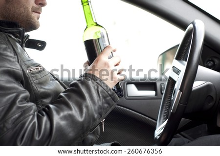 Close up portrait of a handsome man drinking alcohol while driving a car, do not drink and drive concept