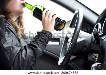 Close up portrait of a beautiful woman drinking alcohol while driving a car, do not drink and drive concept