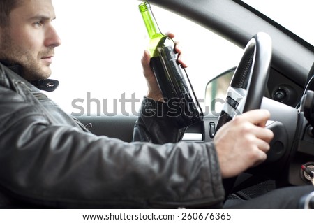 Close up portrait of a handsome man drinking alcohol while driving a car, do not drink and drive concept
