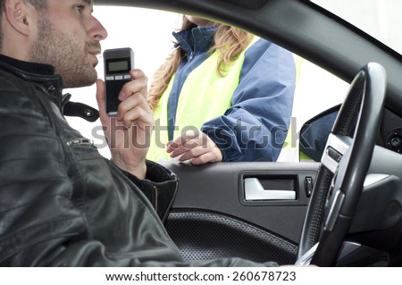 Inside the car view of a young driver subjected to breathalyzer test for alcohol