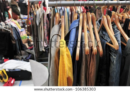 clothes hanging on a rack in a flea market