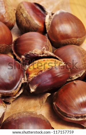 some roasted chestnuts, typical snack in All Saints Day in Spain, on a fall background with dry leaves