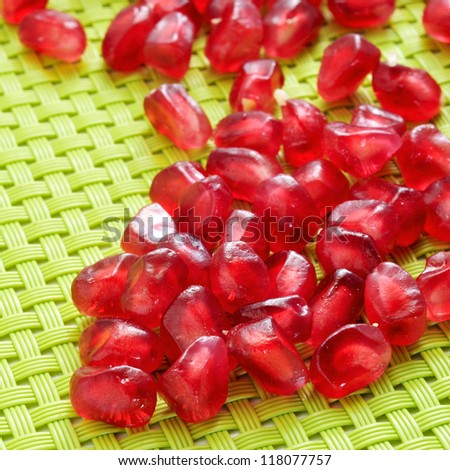 a pile of seeds of pomegranate fruit on a green woven background