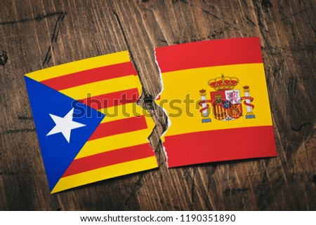 the Estelada, the Catalan pro-independence flag, and the flag of Spain, broken on a rustic wooden surface
