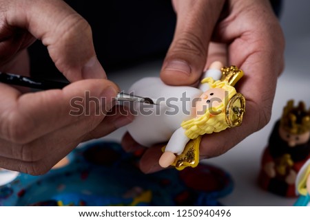 closeup of a caucasian man painting a handmade angel figurine for a nativity scene