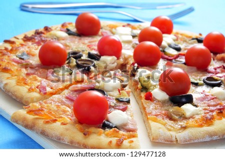 closeup of a pizza with bacon, olives, cherry tomatoes, goat cheese, green pepper and eggplant