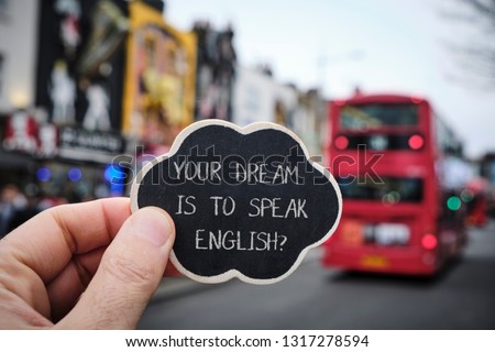 closeup of the hand of a caucasian man holding a black signboard with the question your dream is to speak English written in it, on the street, in the popular Camden Town in London, United Kingdom