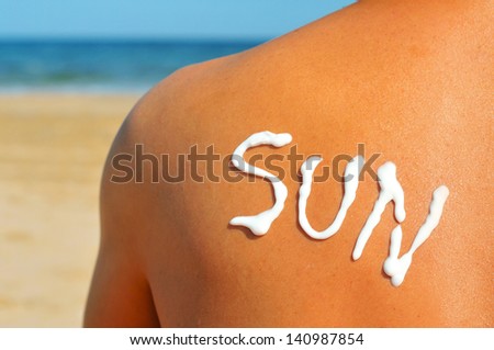 the word sun written with sunblock on the back of a man who is sunbathing on the beach