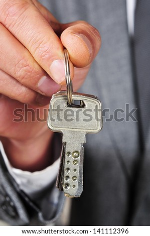 a man wearing a suit with a key ring in his hand