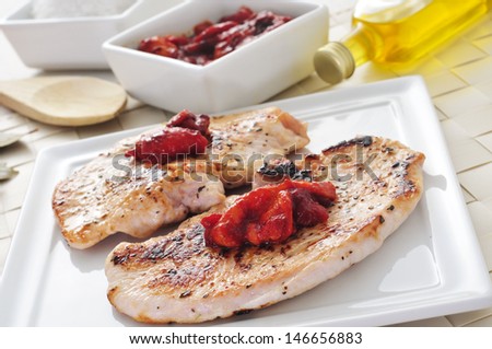 some grilled slices of chicken meat and grilled pepper on a white plate