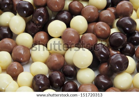 closeup of some different ball-shaped chocolates made with black chocolate, white chocolate and milk chocolate