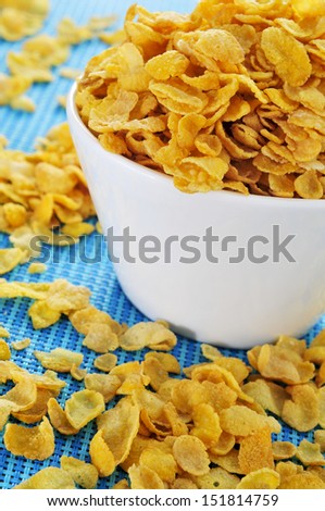 closeup of a bowl with corn flakes on a blue tablecloth