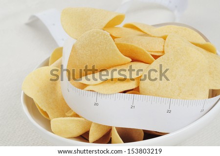 closeup of a bowl with low fat potato chips and a measuring tape