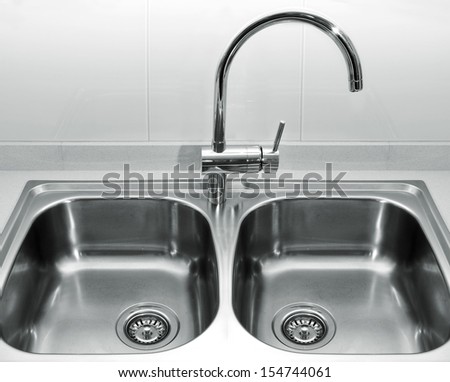 A Double Bowl Stainless Steel Kitchen Sink On A White Granite Worktop