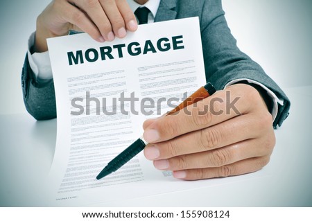 man wearing a suit sitting in a table showing a mortgage loan contract and where the signer must sign